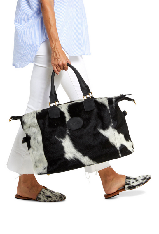 A black and white cowhide weekender bag for travel handcrafted in Kenya that gives back