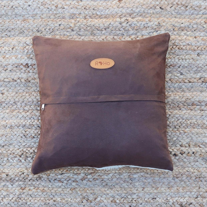 the brown faux suede back of an accent pillow with a RoHo logo in tan leather attached