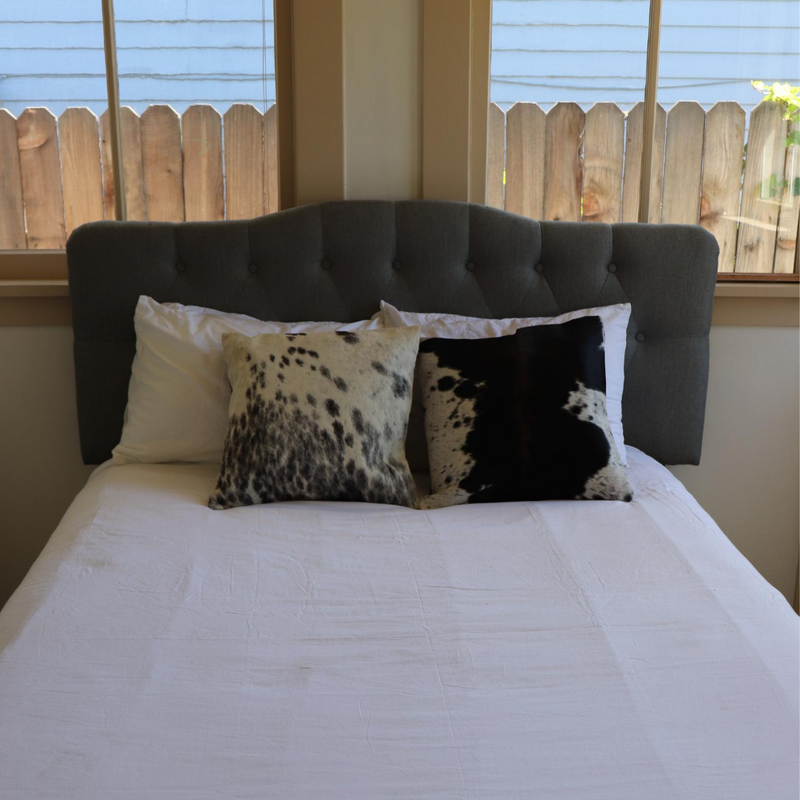 Two Kenyan cowhide pillows displayed on a bed