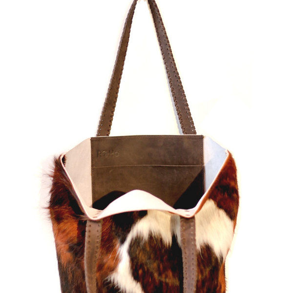 The inside of RoHo's Handcrafted Black & White Cowhide Tote Bag Handcrafted in Kenya with Leather Straps & Gold Brass Button Accents