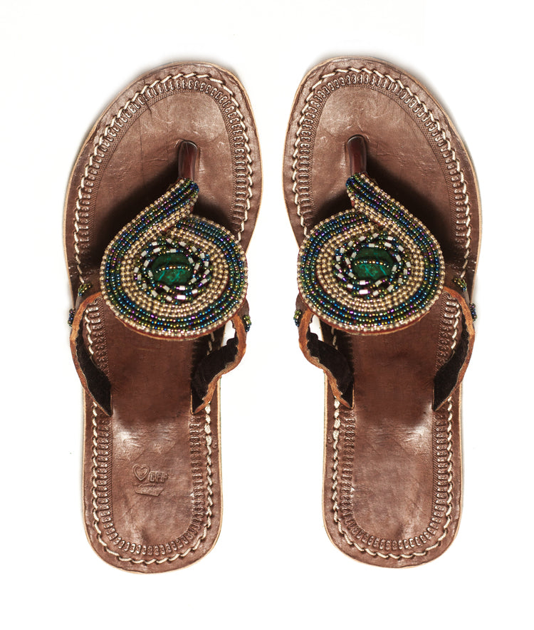 A pair of RoHo beaded green sandals with a large bead in the center handmade by artisans to support them with dignified work