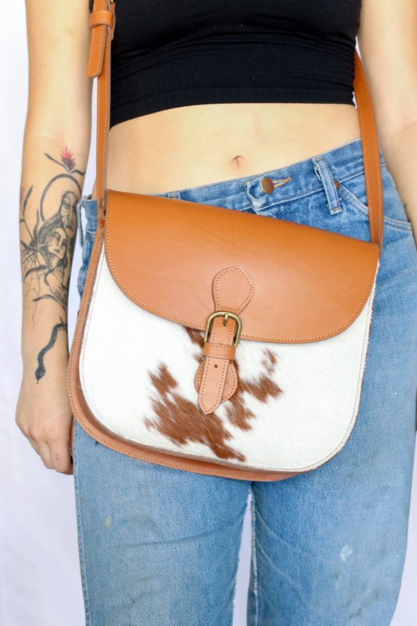 RoHo's artisan made cowhide crossbody purse in tan and white hide and tan finished leather being worn by a model