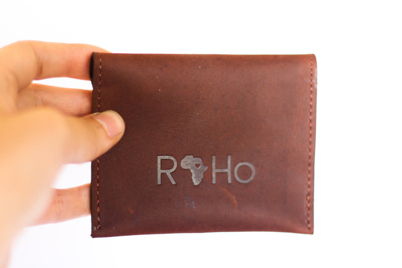 The back of a unique finished brown leather wallet by RoHo that creates impact being held by a model