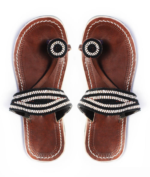 A pair of black and white ethical African beaded leather sandals, RoHo's Rafiki sandal, on a white background