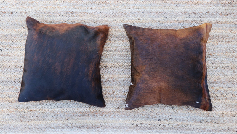 Two brown and black brindle cowhide RoHo accent pillows displayed side by side 