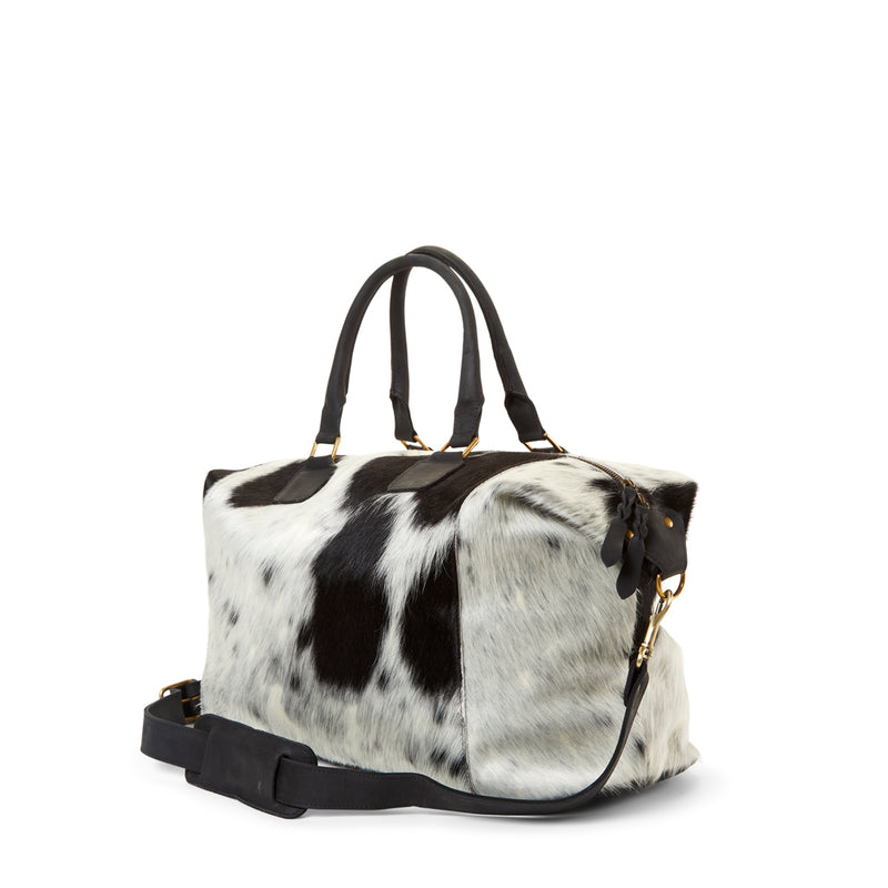 The side of RoHo's black and white cowhide weekender bag with black leather straps handmade in Kenya