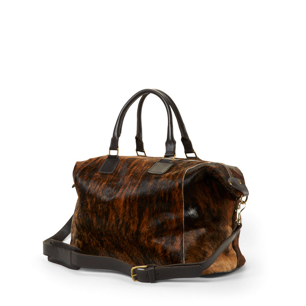 The side of a RoHo's Brindle Brown Cowhide Weekender Duffel Bag, Ethically Handmade in Kenya with Leather Straps
