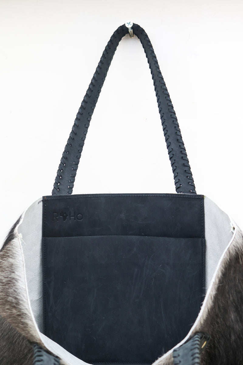 The inside pocket of a unique RoHo grey cowhide tote bucket bag with black handles