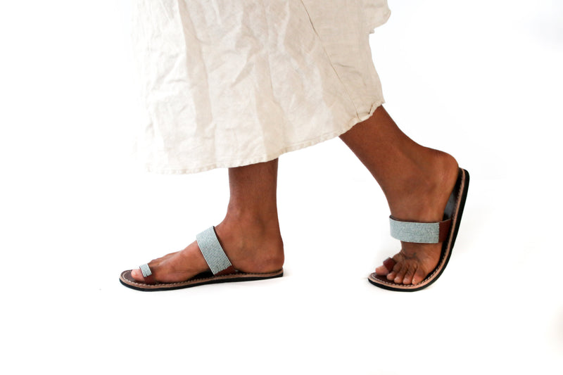 A pair of ethical grey blue Kenyan beaded leather sandals, RoHo's Mkali sandal, on a model